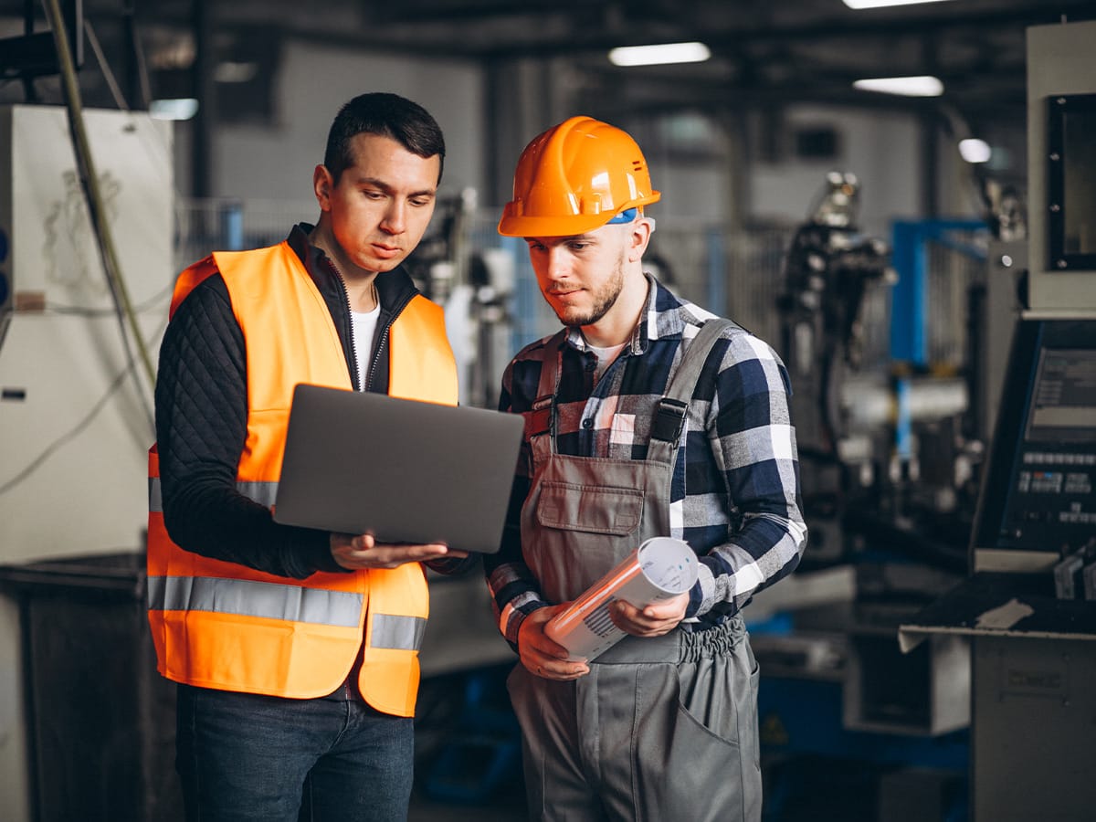 Dos operarios revisan una inspección en un portátil en un taller
